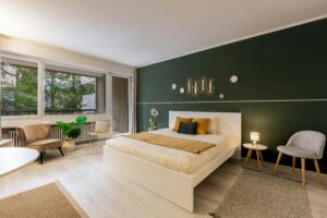 A stylish, modern bedroom with a green accent wall, contemporary decor, and ample natural light.