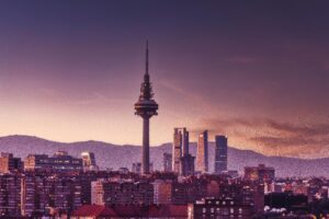 Stunning view of Madrid's skyline at twilight featuring the iconic Torrespaña Tower and mountains in the background.